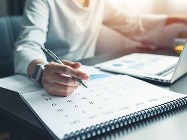 Business woman sitting working and thinking to plan event with calendar and laptop